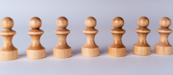 Close up of white wooden chess pieces. Row of white pawns on white background.