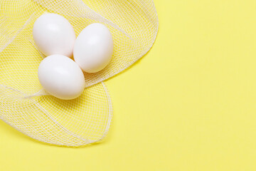 three white chicken eggs on a yellow background. Easter