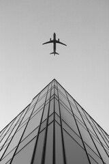 Flying plane over a tall building Black and White Photography
