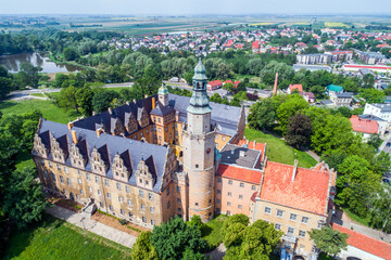 Castle of the Dukes of Oleśnica in Oleśnica. Historic buildings surrounded by trees and the rest of the city.
