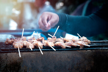  The pork skewers that were placed on the grill. A white smoke rose.Background blur.