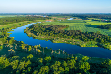 The majestic river meanders between green areas. The blue color contrasts with the greens of fields and meadows.
