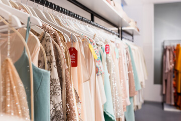 Price tags with sale lettering on hangers with trendy clothes in showroom