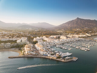Aerial drone perspective of beautiful sunset over luxury Puerto Banus Bay in Marbella, Costa del Sol. Expensive lifestyle, luxury yachts. La concha mountain in background. Nueva Andalucía area