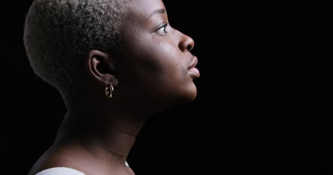 Side view of thoughtful woman smiling over black background