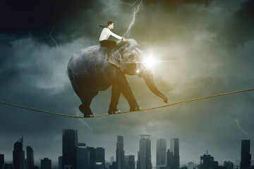 Young businessman riding an elephant on a rope