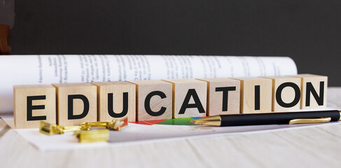 The word EDUCATION is written on wooden cubes near the pen and document.