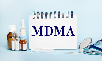 On a light background, a syringe, a stethoscope, vials of medicine, an ampoule and a white notepad...