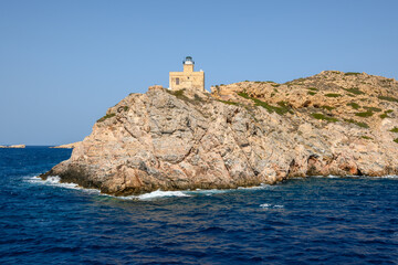The old lighthouse on rocks at the entrance to the harbor bay. Ios island, Cyclades, Greece