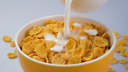 Milk pouring into bowl of corn flakes
