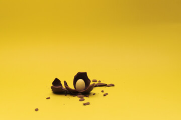 Small white chocolate egg is in crashed milk chocolate egg.