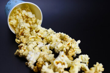 caramel popcorn spilling out of a paper cup on a black background