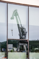 Reflejo de la grúa de un puerto sobre una gran cristalera