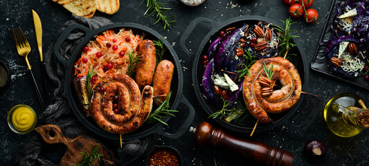 Traditional German dish. Grilled sausages, cabbage, spices and vegetables. Top view. On a black stone background.