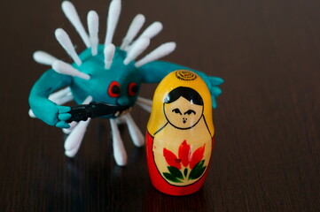 Figure of a virus with a knife. Next to it is a matryoshka doll.