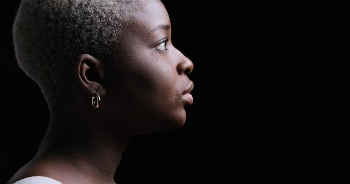Side view of serious woman over black background
