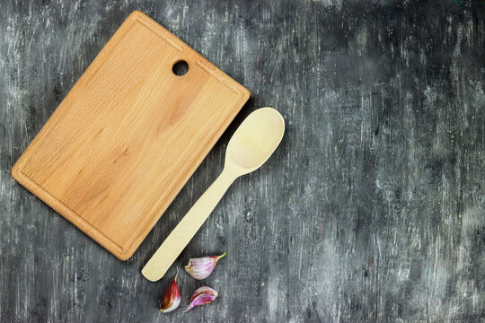 Wooden cutting board, spoon and garlic