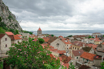 Fototapeta na wymiar View of red roofs of historic old town between mountain and sea in Omis, Croatia.