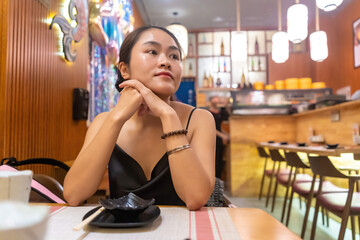 Asian woman waiting in sushi restaurant. Selective focus asian female boring waiting friends or food at restaurant.