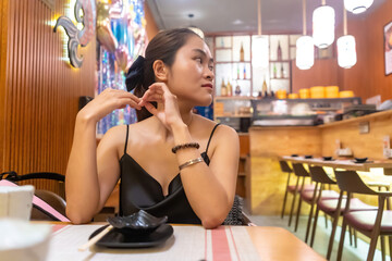 Asian woman waiting in sushi restaurant. Selective focus asian female boring waiting friends or food at restaurant.