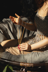 three incense sticks in the hands of a beautiful girl