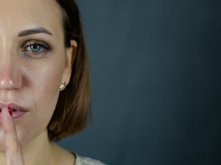 Portrait of a young girl putting her finger to her lips. Fashionable concept.