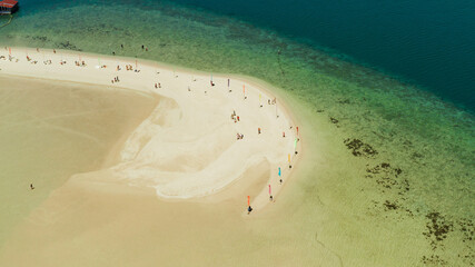 Luli island and sandy beach with tourists, sand bar surrounded by coral reef and blue sea in the honda bay, aerial drone. Tropical island and coral reef. Summer and travel vacation concept