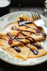 crepes in a white plate thin pancakes pour chocolate syrup flat cake Shrovetide snack healthy meal top view copy space for text food background rustic