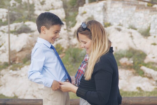 Smiling mother tucking in her son's shirt