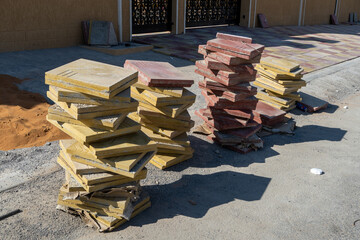 Pile of tiles for Home renovation of concrete sidewalk tiles ourside entrance way of new home with piles of tiles and mortar and cement. DIY new construction concepts.