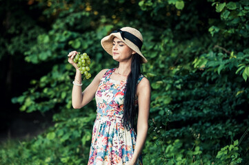 Girl on a picnic eats green grapes fruit.Cute brunette woman harvesting fruits on the farm. High quality photo