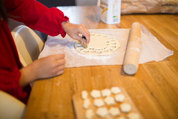 Little girl using cookie cutter to prepare homemade christmas cookies.