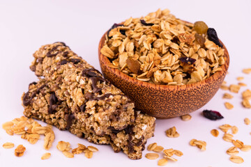 
Granola in a bowl and two bars on a white plate.