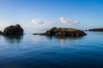 Naklejka premium Rocks protruding from the surrounding blue ocean waters.