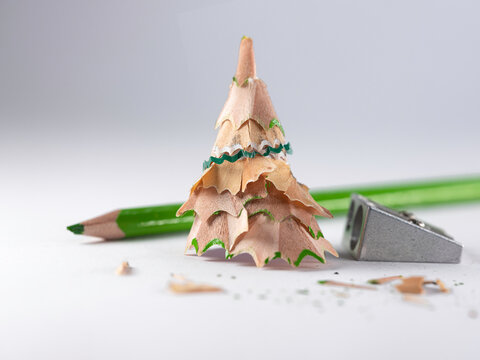 Close-up of a conceptual Christmas tree made from pencil shavings next to a pencil sharpener and green pencil
