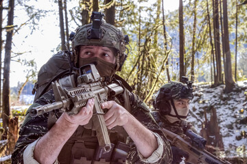 Army Man wearing Tactical Uniform and holding Machine gun in the Outdoor Rain Forest. Winter Warfare. Taken in British Columbia, Canada.