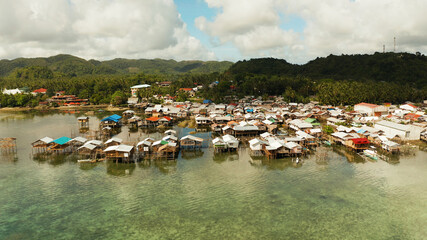 Fishing village with wooden houses standing on stilts in the sea from above. Dapa, Siargao, Philippines.