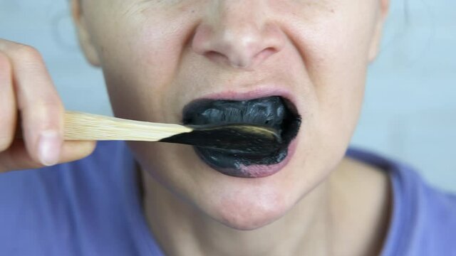 Natural toothpaste. A teen brush her teeth with eco black tooth paste in the bathroom.