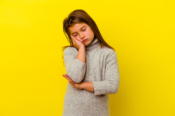 Little caucasian girl isolated on yellow background who is bored, fatigued and need a relax day.