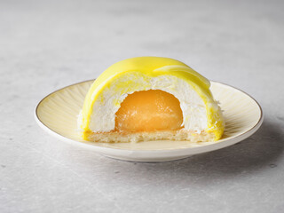 Yellow mousse cake cut in half on a light plate, grey background. Light, bright, airy photo. Lemon Mango Cake. Healthy raw dessert. Space for text. Copy space.  