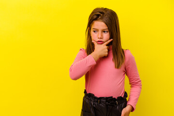 Little caucasian girl isolated on yellow background touching back of head, thinking and making a...