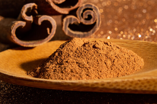 Colher de madeira com p&oacute; de canela e 3 cascas de canela.