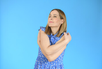 Portrait of a pretty young woman in casual dress hugging herself. Concept of selfish emotion.
