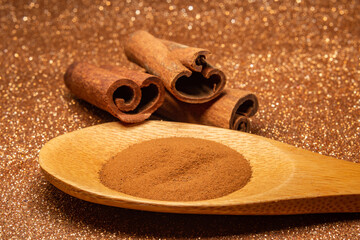 Colher de madeira com pó de canela e 3 cascas de canela.