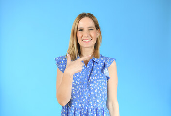 Young woman over isolated blue background pointing finger to the side