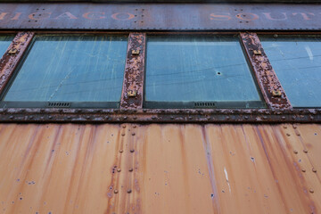 Old passenger train car; rusty peach paint and windows