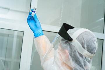 a female medical doctor or a PCR laboratory researcher in a protective suit, helmet and respirator...