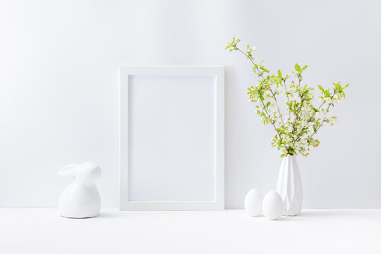 Home interior with easter decor. Mockup with a white frame and spring flowers in a vase on a light background