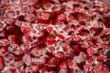 Homemade Strawberry jam in making progress boiling. Process of making homemade strawberry jam. Red sweet syrup boiling on the stove closeup.