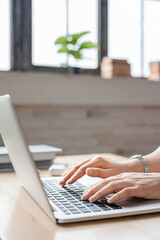 Vertical photo of woman`s hands typing on laptop at the desk